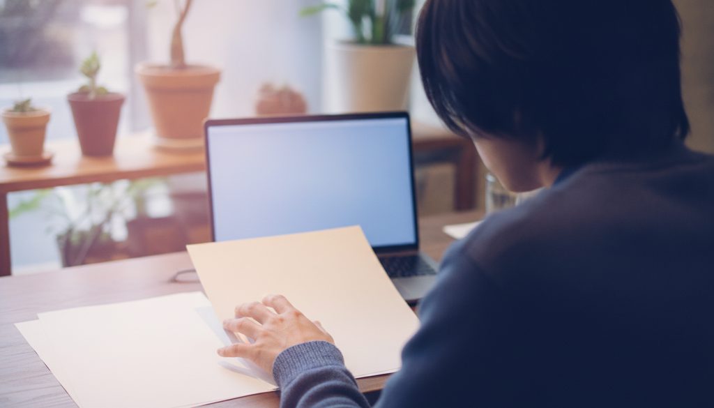 カフェのテーブルで書類を確認する人の後ろ姿