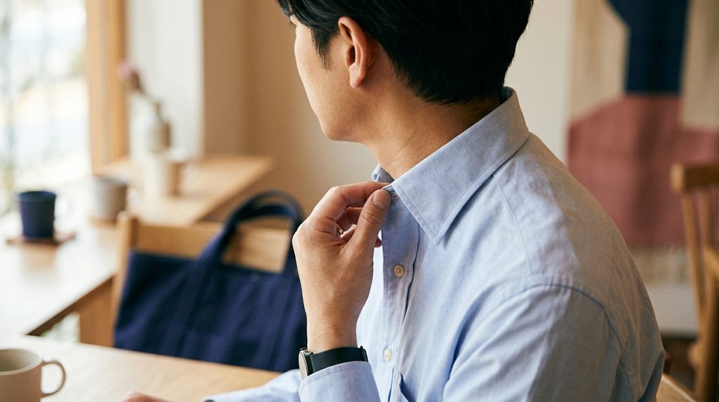 清潔感のあるシャツの襟元を整える男性の手元