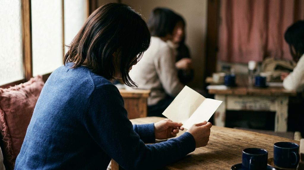 カフェで資料を手に考え込む女性